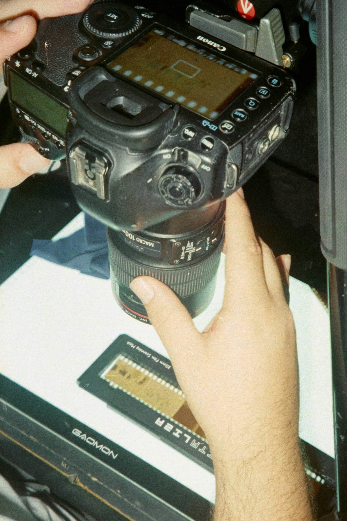 Close-up of a camera with a lens held by hands on a reflective surface.